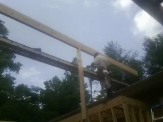 Carpenter setting a ridge beam over a new addition frame — Ice Dam Removal by Roofing Brothers in Christine