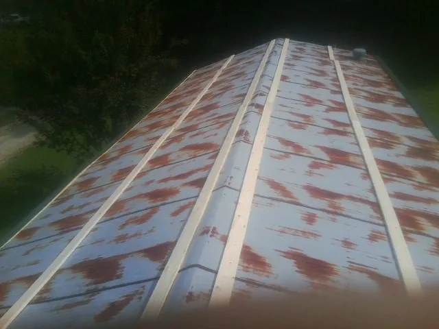 Rusted metal roof panels with new wood purlins before replacement — Storm Damage Roof Repair in Christine by Roofing Brothers
