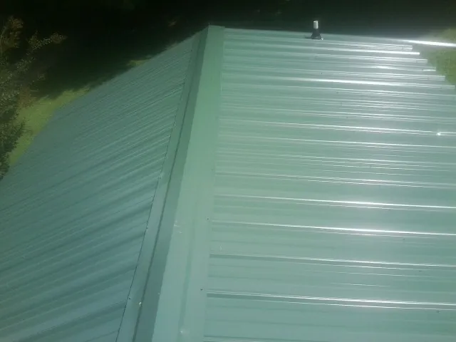 New green metal panels meeting at the ridge of a roof — Flat Roof Repair work by our crew in Christine
