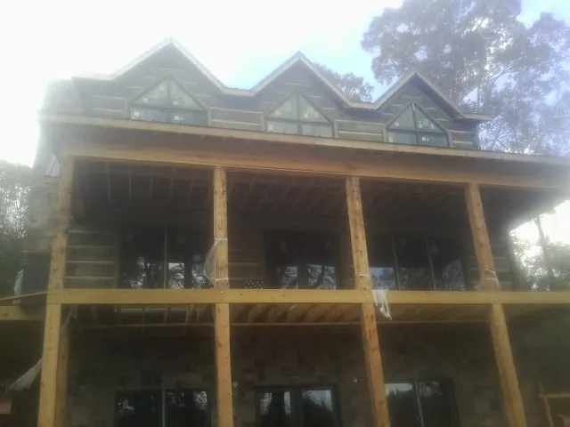 Dormers and porch framing on a large log home under construction — Roof Coating work by our crew in Christine