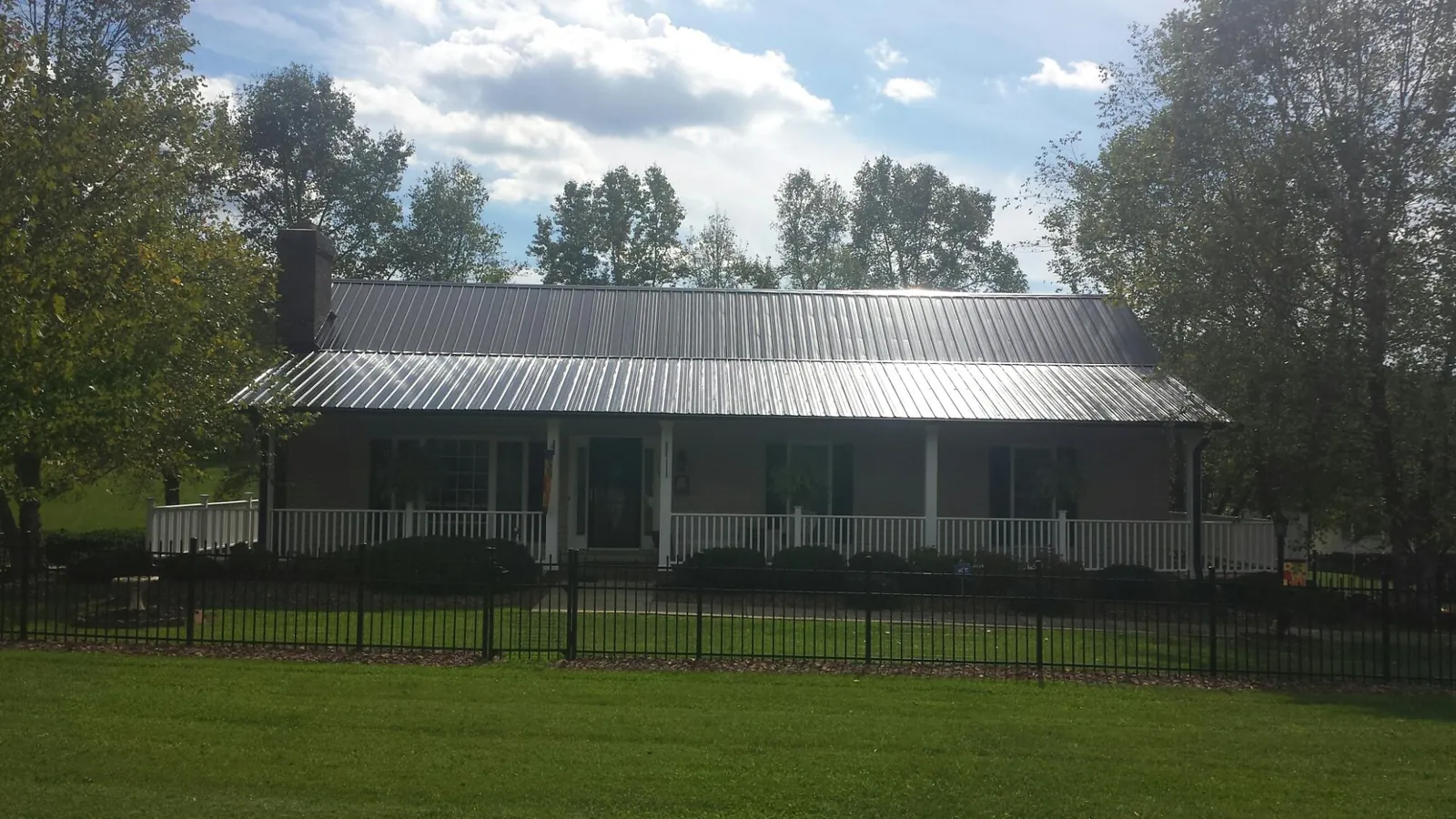 Gray metal roof on a brick ranch with a full width front porch — Gutter Guard Installation work by our crew in Christine