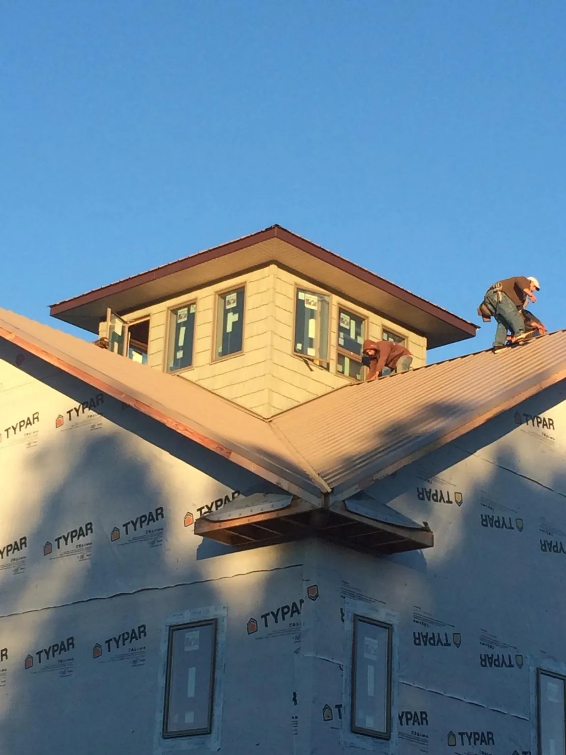 Roofers working around a rooftop cupola on a new metal roof at sunset — Roof Waterproofing in Christine by Roofing Brothers